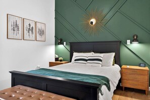 Un dormitorio con cama, mesitas de noche, cómoda y espejo adosado a la pared.