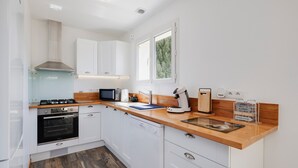 A modern kitchen with white cabinets, a wooden countertop, a gas stove, an oven, a dishwasher, a window, and a sign on the counter. - Holiday Home 'Lacaducee' with Balcony, Wi-Fi and Air Conditioning (Peujard)