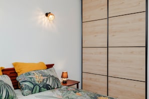 A bedroom with a bed, a nightstand, a lamp, and a wall-mounted light fixture.