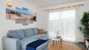 A modern living room with a light blue sofa, a small round table, and a large window with sheer curtains. - Holiday Home 'Lacaducee' with Balcony, Wi-Fi and Air Conditioning (Peujard)