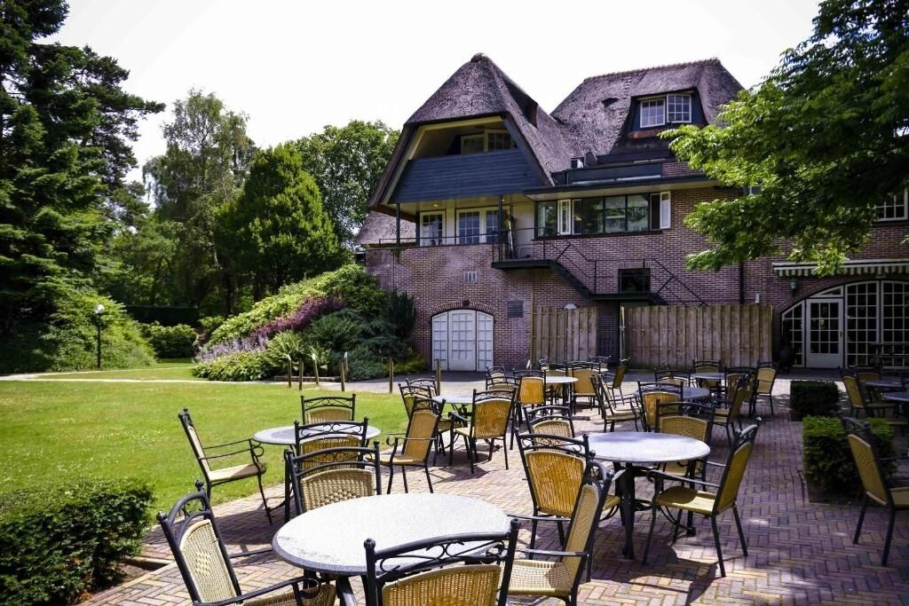 A brick building with a large patio area featuring outdoor tables and chairs.