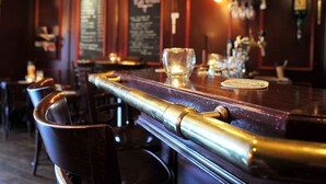 Un espace bar avec un comptoir élégant, un verre et un tableau affichant le menu en arrière-plan.