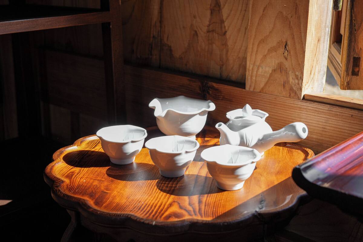 Een houten tafel met witte keramieken kommen en een karaf.