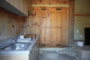 Une cuisine avec des meubles en bois, un évier et un foyer en pierre.