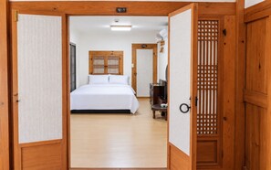 A hotel room with a bed, a desk, and a traditional wooden door.