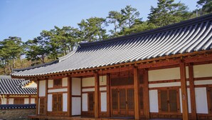A traditional wooden building with a tiled roof, wooden doors, and a stone base.