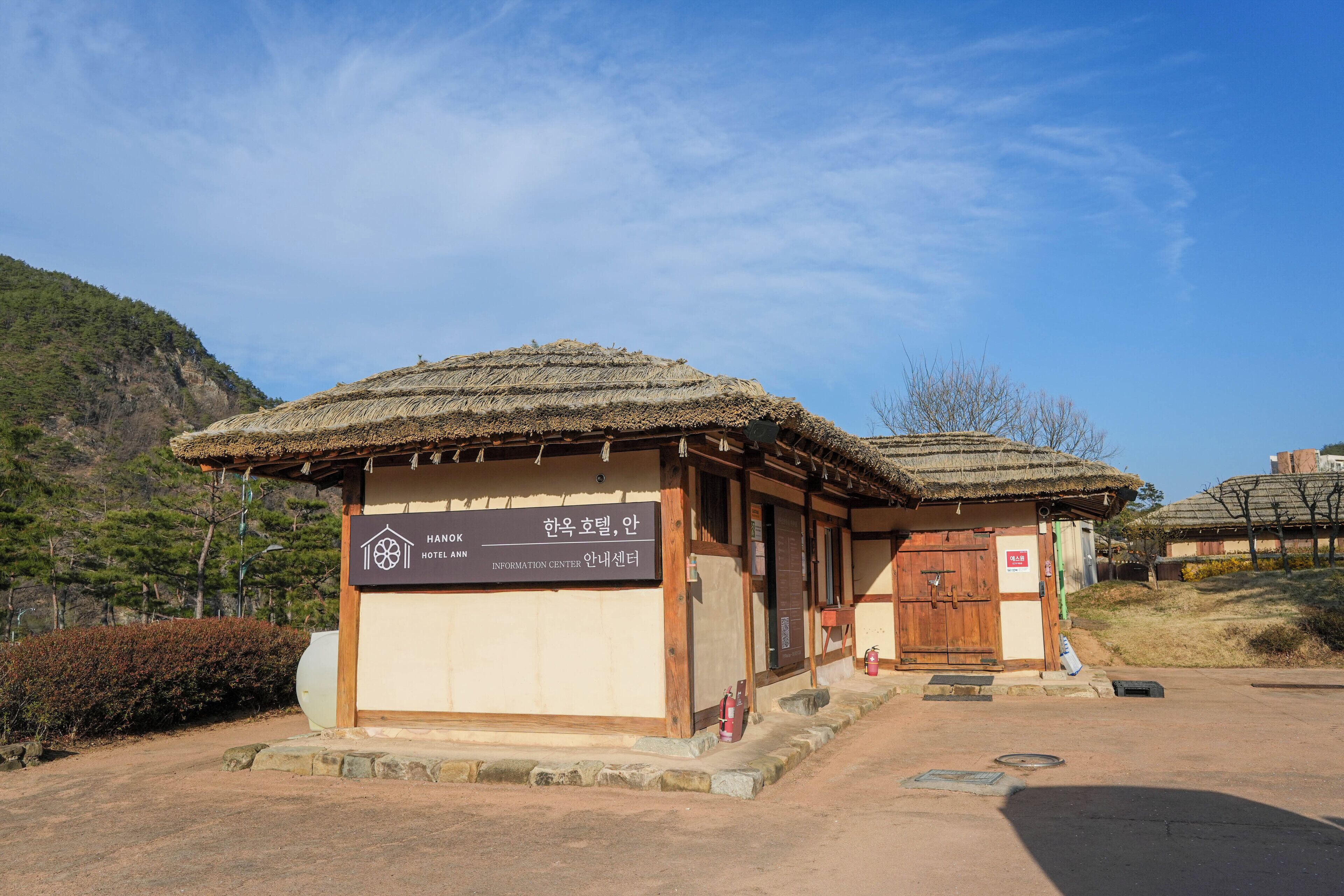 Un edificio de estilo coreano tradicional con techo de paja, puerta de madera y un letrero que indica que es un centro de información.