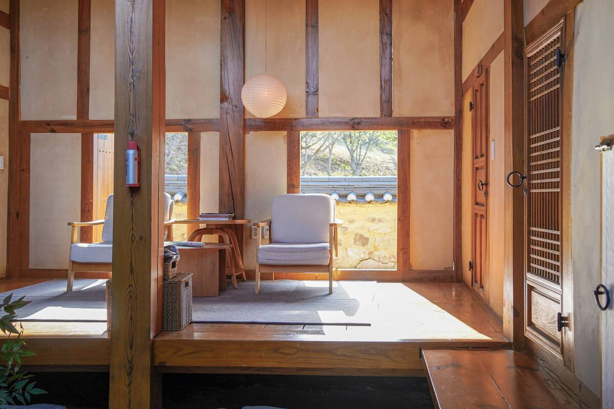 Een traditionele Japanse kamer met tatami vloerbedekking, een lage houten tafel, een gewatteerde stoel en een schuifdeur.