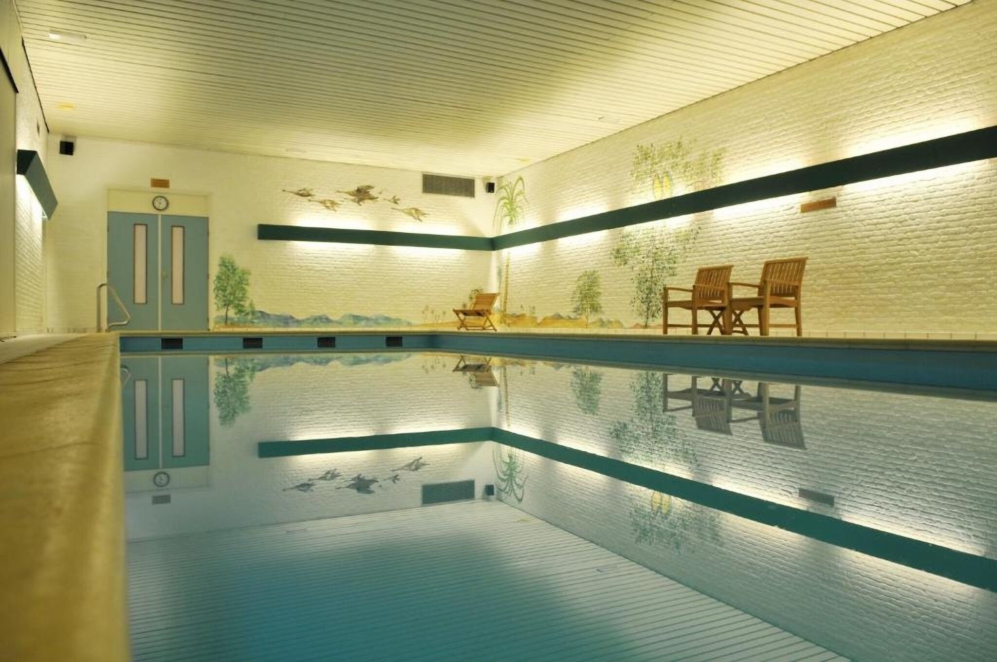 Ein Schwimmbad mit Wandmalerei, zwei Türen und einer Bank.