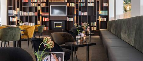 Une bibliothèque moderne équipée d’un canapé, de fauteuils, d’un téléviseur et d’étagères.