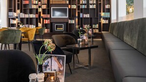 A modern library with a sofa, chairs, a TV, and bookshelves.