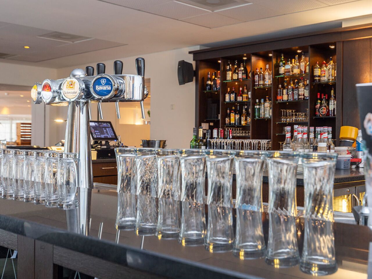 Baaritiskialue, jossa on useita hanahanoja, hyvin varustettu alkoholihylly ja rivi tyhjiä laseja.