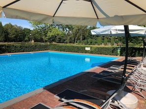 A swimming pool with lounge chairs and umbrellas.