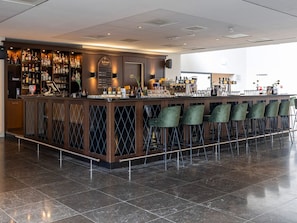 A bar area with a long counter, multiple shelves of bottles, and several green chairs. - Quiet Suite Perfect for Adventure and Historical Discoveries (Doorwerth)