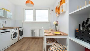 Kompakti keittiö, jossa on pyykinpesukone, ruokapöytä tuoleineen ja ikkuna, josta on näkymä.