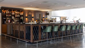 A bar area with a long counter, multiple shelves of bottles, and several green chairs. - Doorwerth Hotel-Style Stay in Nature Near Arnhem & Hiking Trails - 3 Units (Doorwerth)