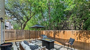 Een achtertuin met vuurkorf, buitenmeubilair, een barbecue en een pergola.