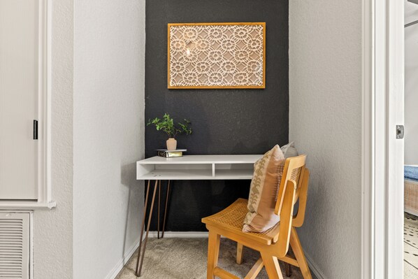 A corner room with a desk, chair, and a decorative wall piece.