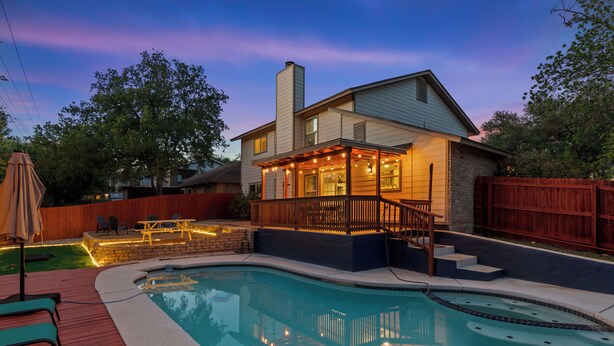 Une maison avec une piscine, une terrasse en bois et un patio couvert.