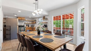 Une cuisine moderne avec un coin repas, comprenant une grande table en bois, des chaises et une vue sur l’extérieur.