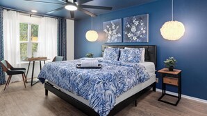 Une chambre à coucher avec un lit, un ventilateur de plafond, une table de chevet et une fenêtre.