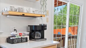 Une cuisine dotée de meubles en bois, d’un coin café et offrant une vue sur l’extérieur grâce à une porte-fenêtre coulissante.