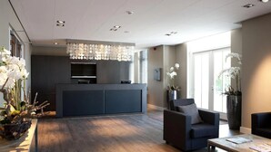 Un interior moderno con mostrador de recepción, zona de estar y ventanas amplias.