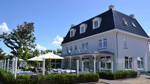 Ein Gebäude mit einem Schild, auf dem 'Restaurant DUNZICHT' steht, Außenbereich mit Sonnenschirmen und einem Kiesplatz davor.