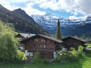 A mountain lodge with multiple wooden cabins, surrounded by lush greenery and snow-capped mountains in the background. - Chalet Rotebächli by Interhome (Lenk)