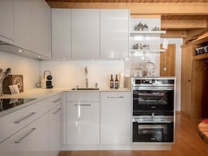 A modern kitchen with white cabinetry, a stainless steel sink, and a built-in oven. - Chalet Rotebächli by Interhome (Lenk)
