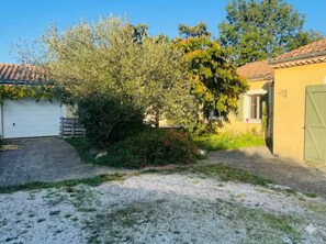 Il s’agit d’une propriété résidentielle dotée d’un garage, d’une allée en gravier et d’un jardin agrémenté d’arbres et d’arbustes.