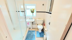 A small bathroom with a toilet, sink, and a window with flowers.