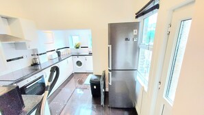 A compact kitchen with a washing machine, a refrigerator, and a window with a view.