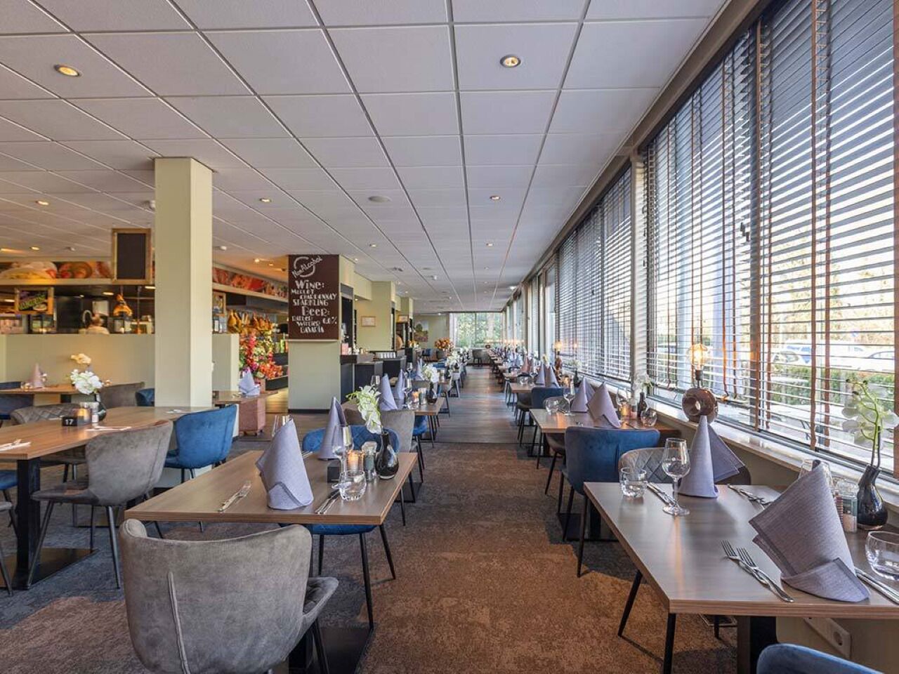 Een restaurant met tafels en stoelen, een bar en grote ramen.