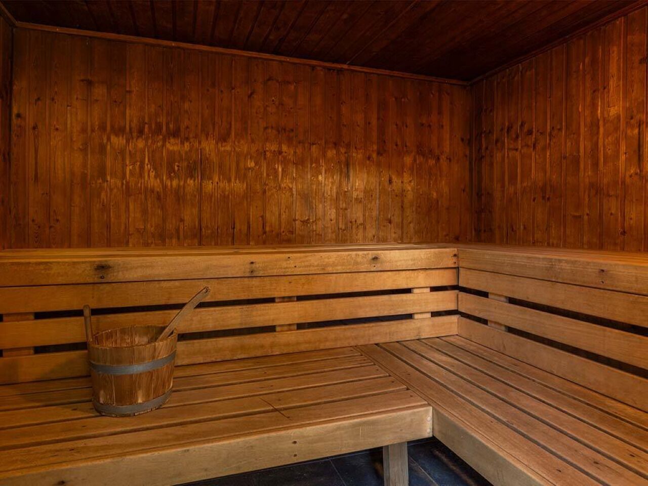 Un sauna en bois avec des bancs et un seau en bois.