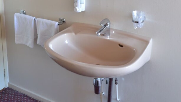 A bathroom with a sink, mirror, towel rack, and a wall-mounted shelf. - Short Drive to Beach! Free Breakfast and Parking, Close to Brielse Meer! (Brielle)