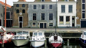 A canal with boats docked, a building with a brick facade, and a bicycle parked outside. - Short Drive to Beach! Free Breakfast and Parking, Close to Brielse Meer! (Brielle)