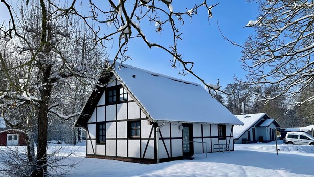 A traditional half-timbered house with a steeply pitched roof, surrounded by snow-covered ground and trees. - Our Knüllperle half timbered holiday home next to Silbersee lake in Frielendorf (Frielendorf)