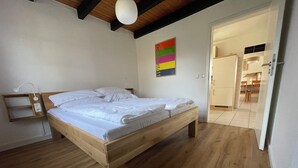 A wooden bed in a room with a white wall and a rainbow poster. - Our Knüllperle half timbered holiday home next to Silbersee lake in Frielendorf (Frielendorf)
