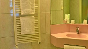 A bathroom with a white towel rack, a pink sink, and a mirror.