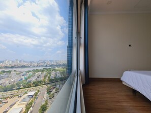 A bedroom with a view of a cityscape, a bed, and a window. - 1 Bedroom Apartment for Rent at Vinhomes Central Park (Thành phố Hồ Chí Minh)