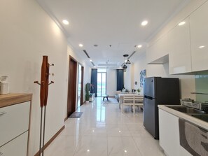 Uma cozinha moderna com geladeira, uma área de jantar com mesa e cadeiras, e um corredor que dá para uma varanda.