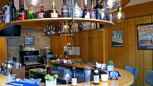 A bar area with a curved counter, various liquor bottles, a coffee machine, and a television mounted on the wall. - Relaxing Place with On-site Dining, Breakfast and Access to Town Walks! (Brielle)