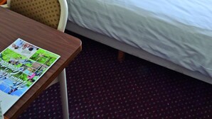 A single bed with white bedding, a wooden headboard, a small table with a magazine, a chair, and a potted plant. - Relaxing Place with On-site Dining, Breakfast and Access to Town Walks! (Brielle)