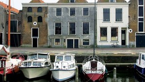 A canal with boats docked, a building with a brick facade, and a bicycle parked outside. - Relaxing Place with On-site Dining, Breakfast and Access to Town Walks! (Brielle)