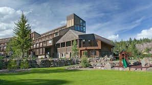 A modern building with a stone facade, large windows, and a playground area with a slide.