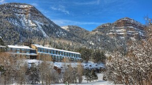 Ett hotell med modern design, omgivet av snötäckta berg och träd.