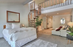 A bedroom with a large bed, a staircase, a sofa, and a mirror. - Tamarron Treetop | AC, Pool, Hot Tub, Golf & Ski (Durango)