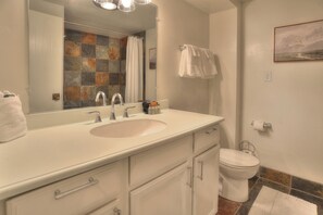 A bathroom with a white sink, two faucets, a mirror, a toilet, and a towel rack. - Tamarron Treetop | AC, Pool, Hot Tub, Golf & Ski (Durango)