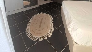 Moderni hotellihuone, jossa on sänky, sohva, pieni keittiö ja suuri peili.